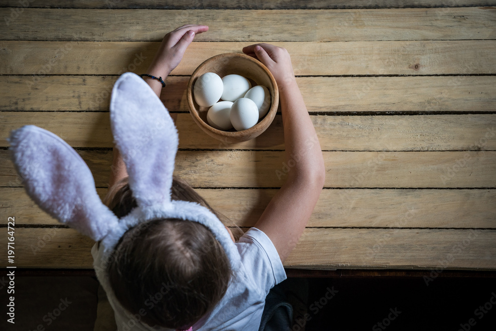 Fototapeta premium the child prepares for Easter, paints eggs in the ears of a rabbit