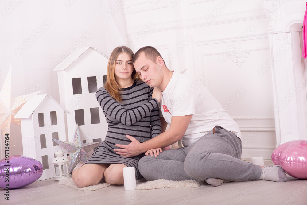 Fototapeta premium Young pretty pregnant woman and her husband at home