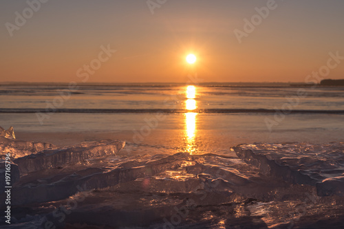 A beautiful sunrise, sunset on the lake, in the foreground, ice floes pile up and break the golden light. Concept vacation and travel or landscapes