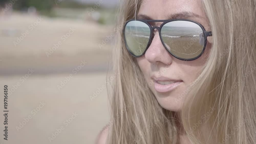Close up portrait of beautiful young blonde woman in sunglasses enjoying view of tropical beach slow motion Close up portrait of beautiful young blonde woman in sunglasses enjoying view of tropical beach slow motion