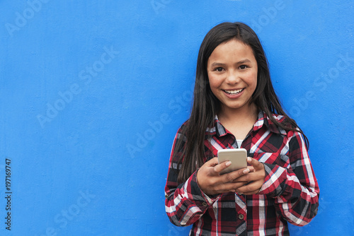 Portrait of cute latino girl using the mobile in the street. photo