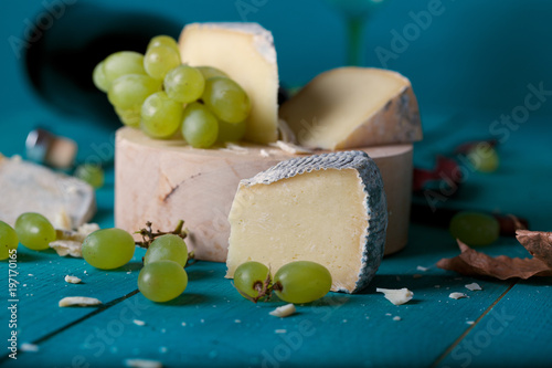 Cheese, grapes and wine on wooden cyan surface. photo