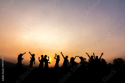 Silhouette of cheering young generation Stand on the mountain at sunset. Business concept idea