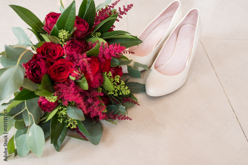 Φωτογραφία Lush bridal Bouquet of red roses and a lot of greenery with elegant bridal shoes