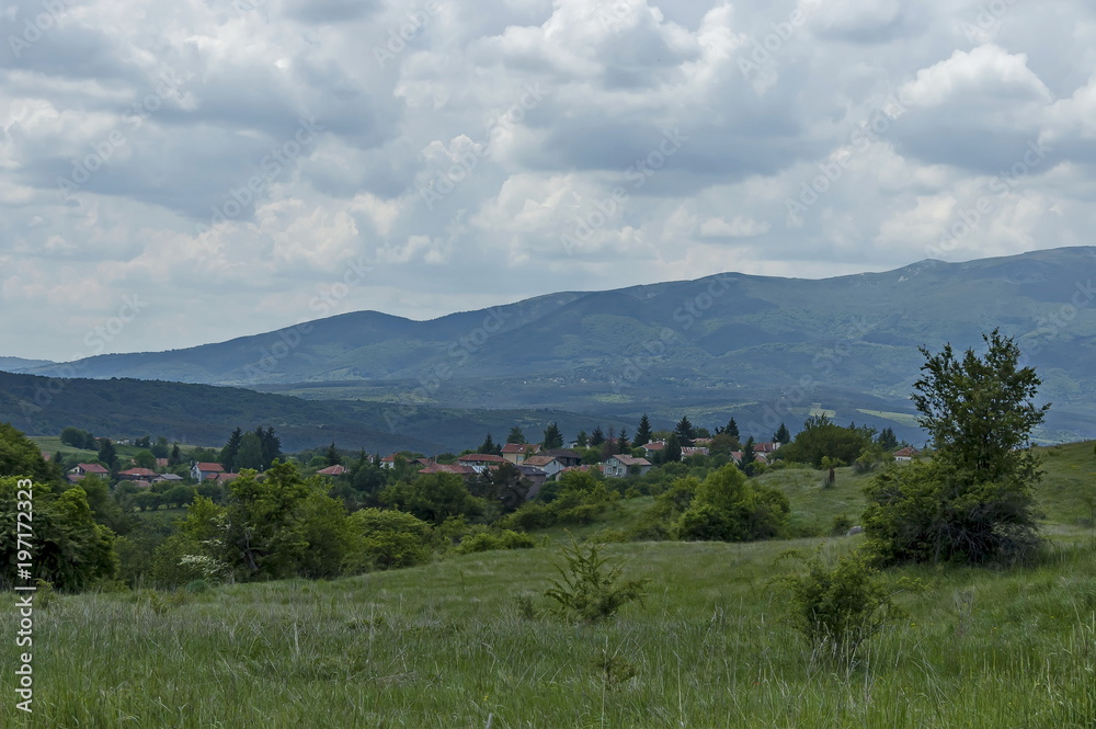 Scene with mountain glade, forest and residential district of bulgarian village Plana, Plana mountain, Bulgaria  