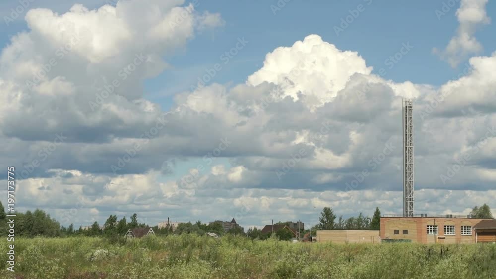 Environmentally friendly little industrial plant. High chimney with clear smoke on a background of blue sky with floating white clouds in the summer Environmentally friendly little industrial plant. High chimney with clear smoke on a background of blue sky with floating white clouds in the summer