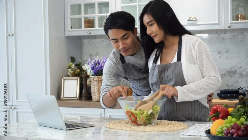 The happy couple use laptop computer while cooking in kitchen The happy couple use laptop computer while cooking in kitchen