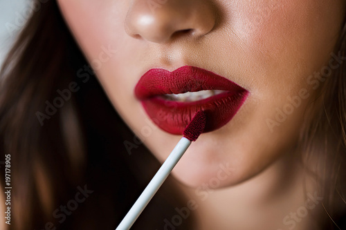 Professional make up. Makeup artist apply lip gloss. Close up of woman face. Red Lipstick. © liliyabatyrova