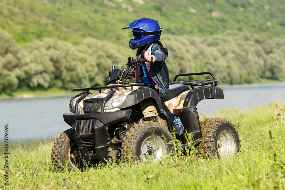 The boy is traveling on an ATV.