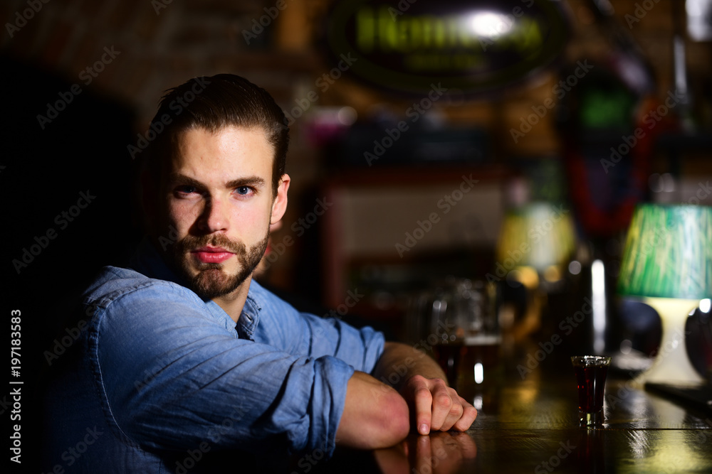 Bearded man drink alcohol on blurred bar background.