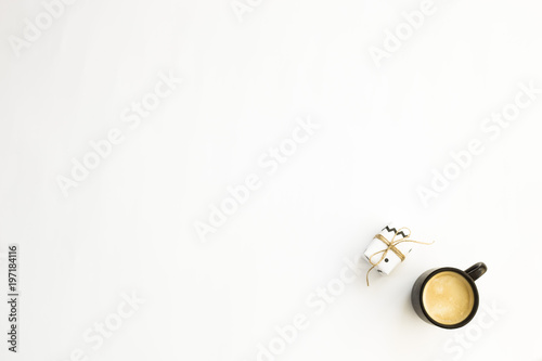 A cup of coffee and one small minimalist gift on a white background. Copyspace. Flat lay, top view