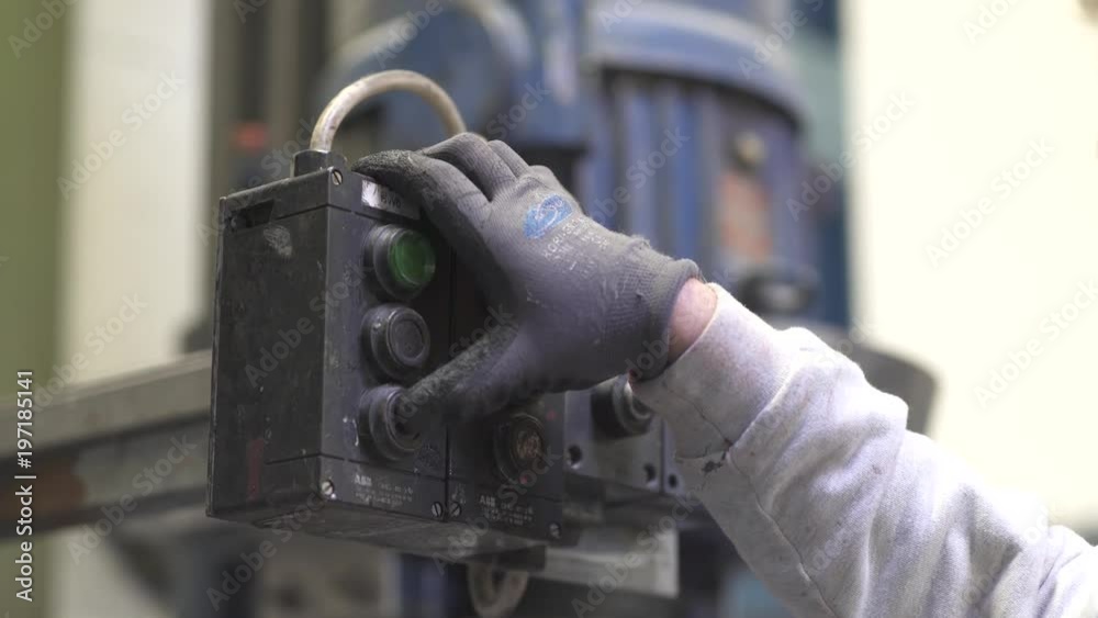 a worker presses a button to start the press machine. a worker presses a button to start the press machine.