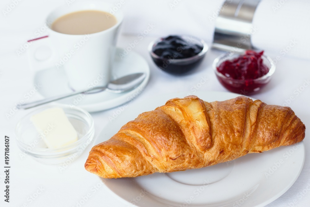 Croissant breakfast served with jams, butter and a cup of coffee with milk Croissant breakfast served with jams, butter and a cup of coffee with milk
