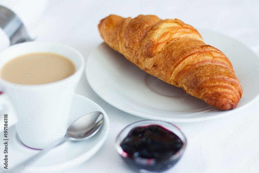 Croissant with butter, blueberry jam and a cup of coffee. Perfect coffee break setup