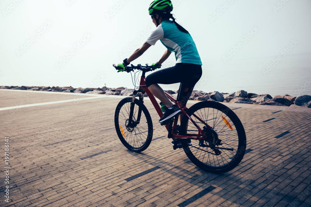 Obraz premium female cyclist riding mountain bike on seaside