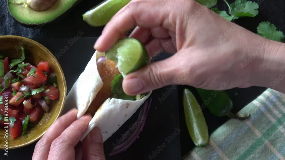 Eating Fish Taco on a soft flour tortilla with salsa and avocado
