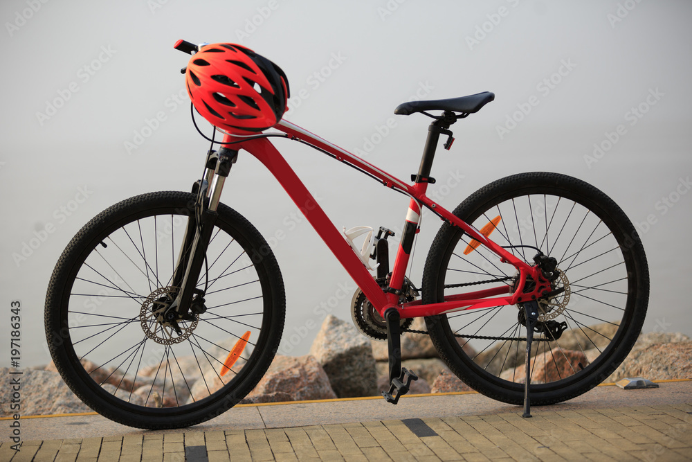 Naklejka premium red mountain bike and helmet on seaside
