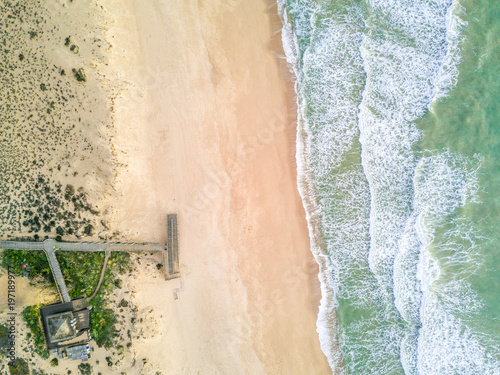 Pier leading to sandy beach and waves in Quinta do Lago, Almancil, Algarve, Portugal photo