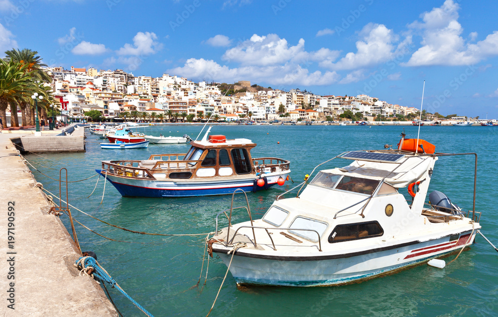 Greece. Crete. Embankment in the town of Sitia. Traditional fishing and pleasure boats at quay in sunny summer day. Beautiful seascape