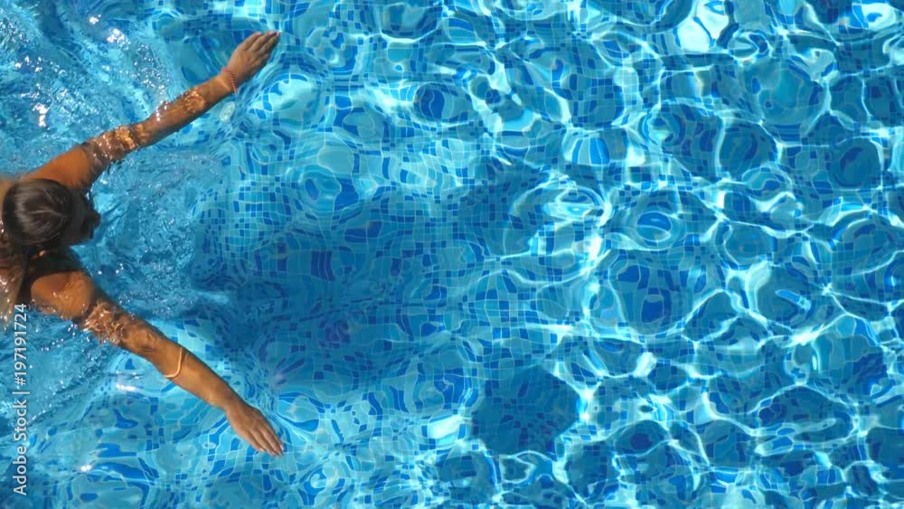 Top view of unrecognizable young girl in red bikini swimming across the ...