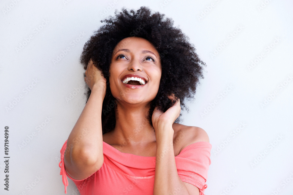 Close up african woman smiling with hands in hair and looking up on white background Close up african woman smiling with hands in hair and looking up on white background