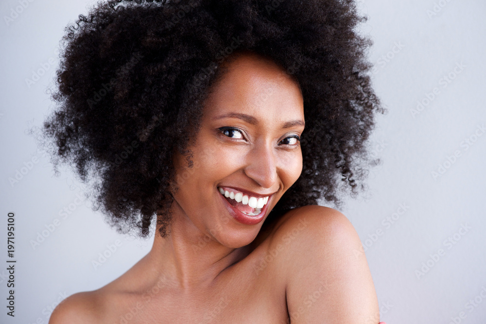 Close up black woman with naked shoulders smiling on gray background Close up black woman with naked shoulders smiling on gray background
