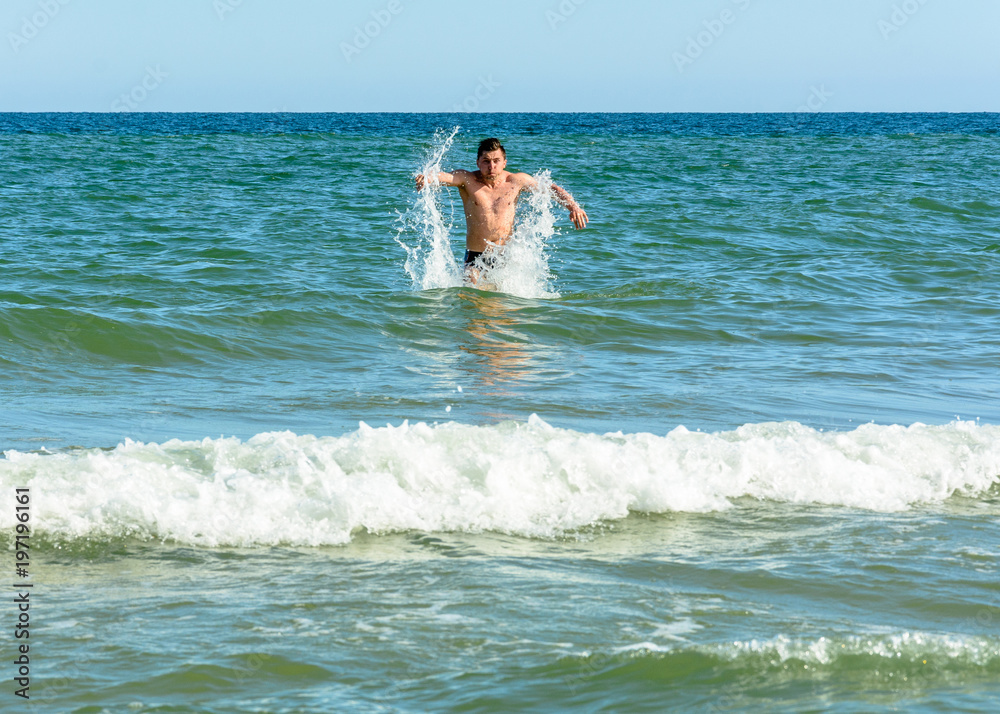 A sports man quickly runs from the beach in the sea waves