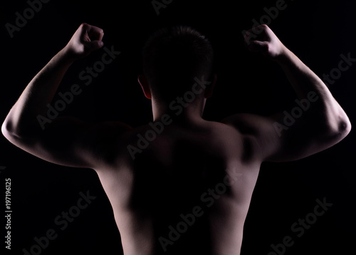 Portrait of sportsman with musclein studio. Low key isolated photo with free blank space for your text.
