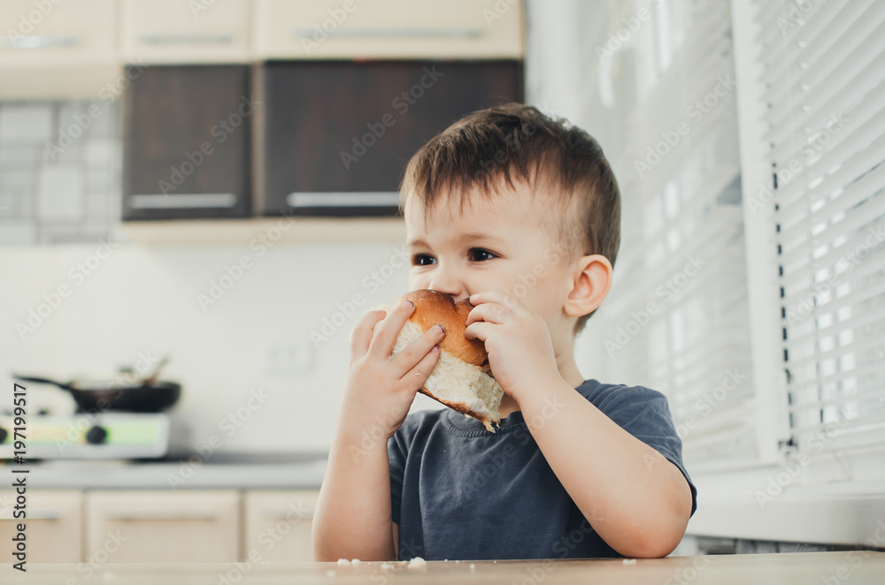 the child in the kitchen eating a sweet bun, very tasty the child in the kitchen eating a sweet bun, very tasty