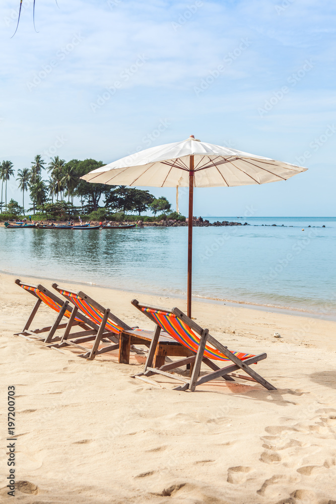 Lounge chairs under umbrella on beach.