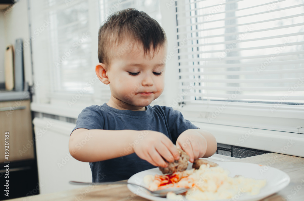 little baby boy in the kitchen eating pasta with cutlets, very tasty little baby boy in the kitchen eating pasta with cutlets, very tasty