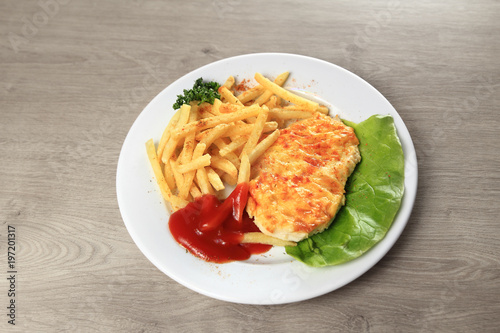chicken in cheese and garnish on a white plate on wooden background