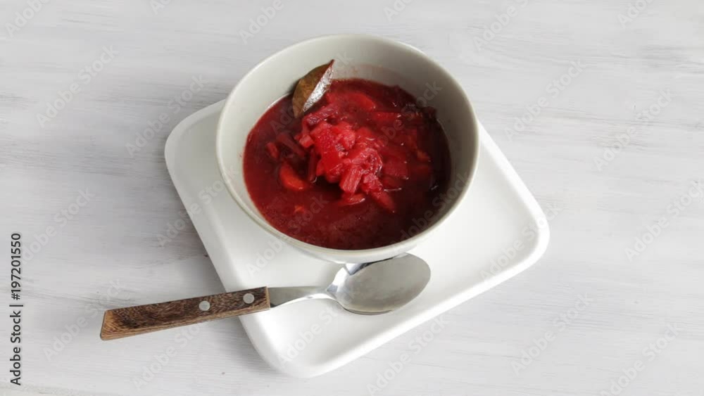 Steaming red beet soup in porcelain bowl on wooden table. High angle. Selective focus. Steaming red beet soup in porcelain bowl on wooden table. High angle. Selective focus.