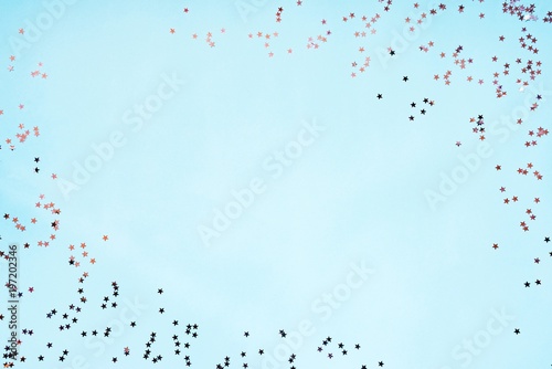 Star shaped silver sequins over blue background. Copy space.