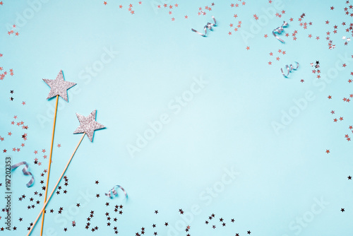 Two silver party magic wands, sequins and ribbons on a blue background. Copy space.