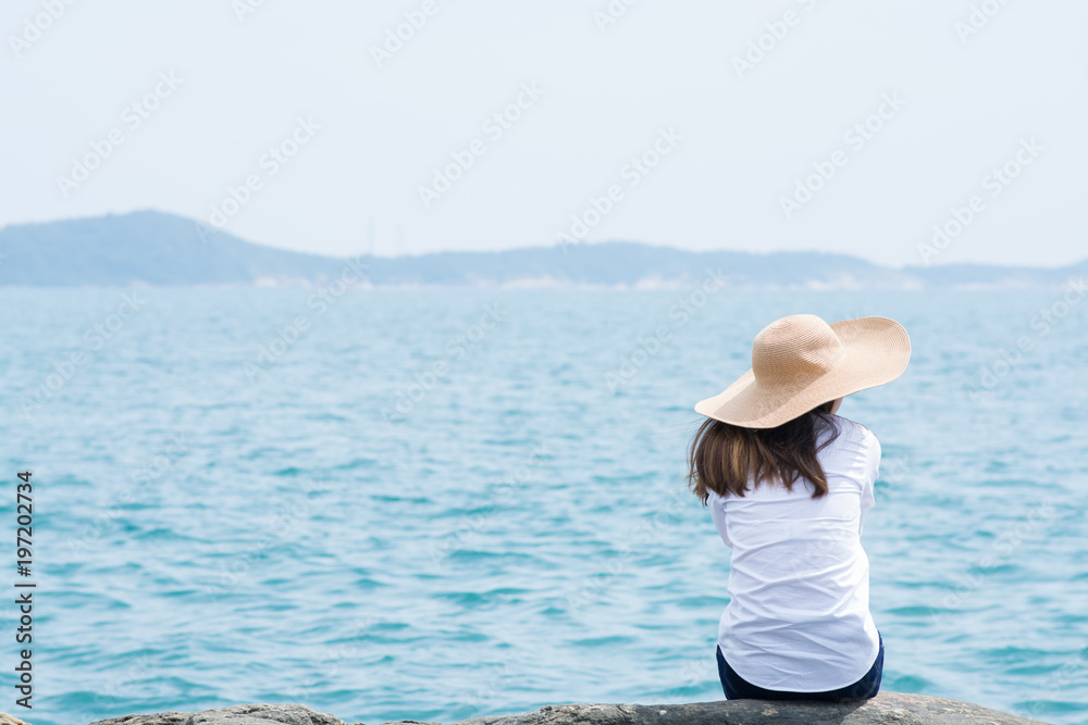 Lonely woman sitting alone on a rock at sea