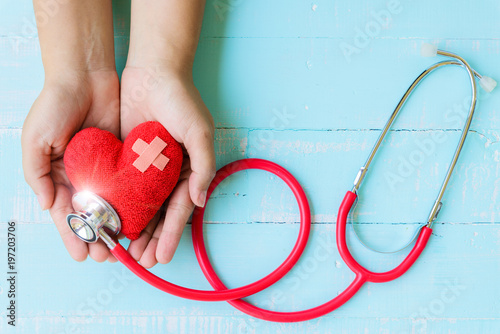 World health day, Healthcare and medical concept. Woman hand holding red heart with Stethoscope,  thermometer and yellow Pill on Pastel white and blue wooden table background texture. photo