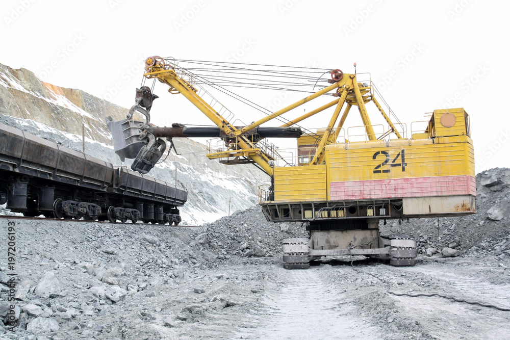 The excavator loads the stones into the cars. Loading ore into the railway cars in the quarry.