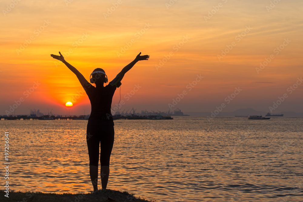 Silhouette women runner listening music and feeling freedom, happy and enjoying nature sunset.  Lifestyle and Healthy Concept.