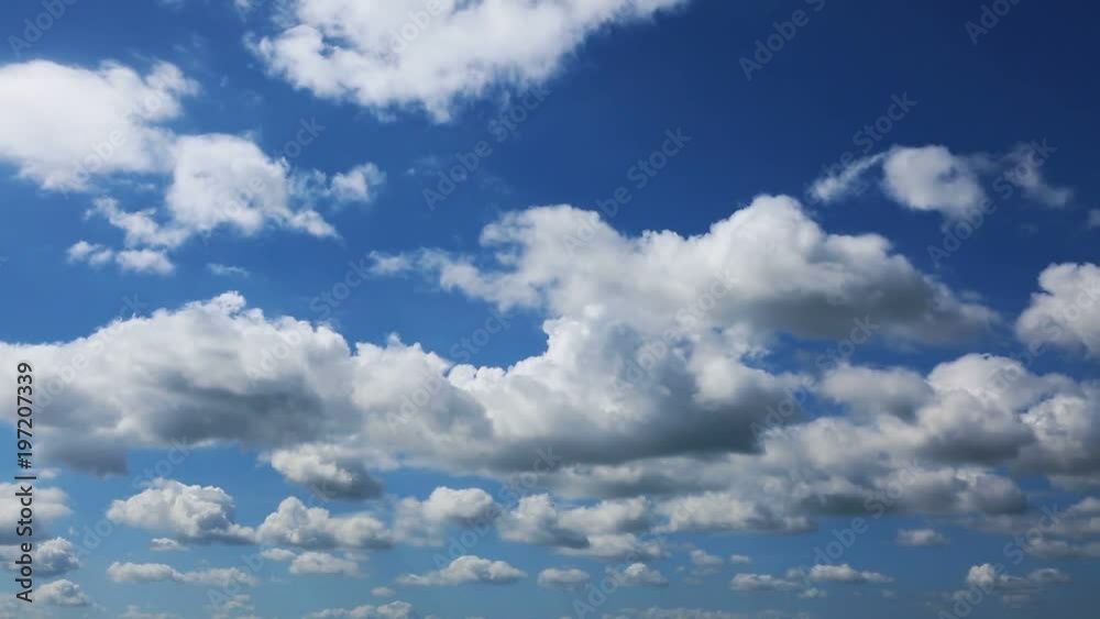 Loop of white running clouds over blue sky.