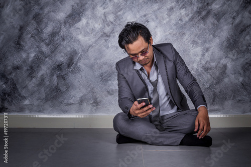 depressed businessman with mobile phone and sitting on the floor