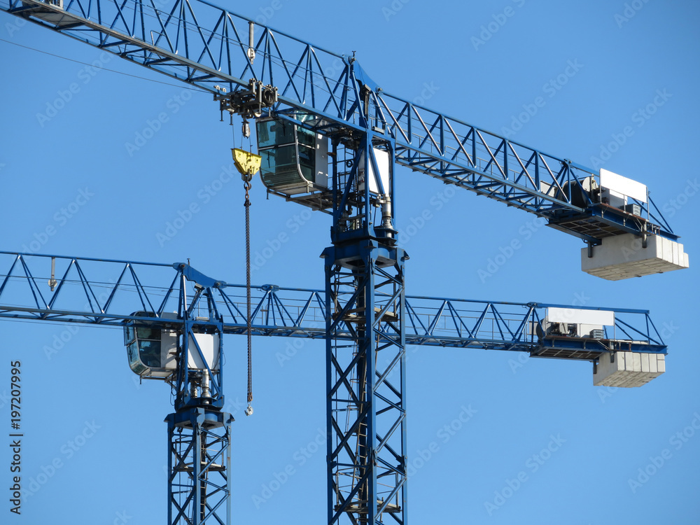Construction cranes on the background of clear blue sky Construction cranes on the background of clear blue sky