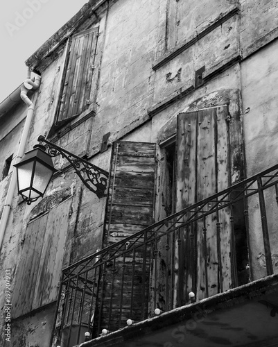 Old typical Mediterranean house with wooden shutters and stucco wall with peeling paint in Arles, Bouches-du-Rhone, Provence-Alpes-Cote d'Azur, France. Black white historic photo.
