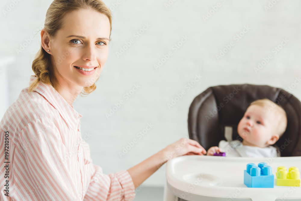 Portrait of mother with infant daughter sitting in baby chair with plastic blocks Portrait of mother with infant daughter sitting in baby chair with plastic blocks