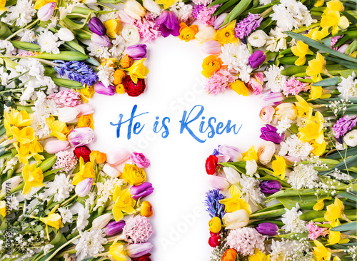 Photography A cross on a colorful flower background. Easter flat lay.