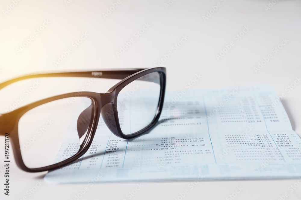 Glasses with bank account passbook for savings financial and accounting concept. Glasses with bank account passbook for savings financial and accounting concept.