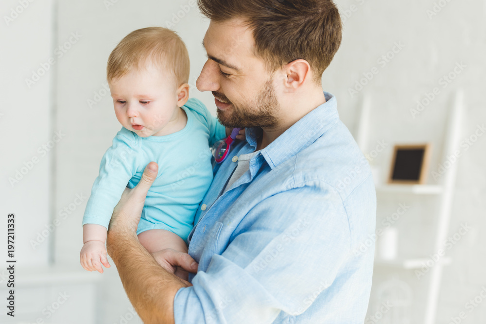 Smiling father holding infant daughter in hands Smiling father holding infant daughter in hands