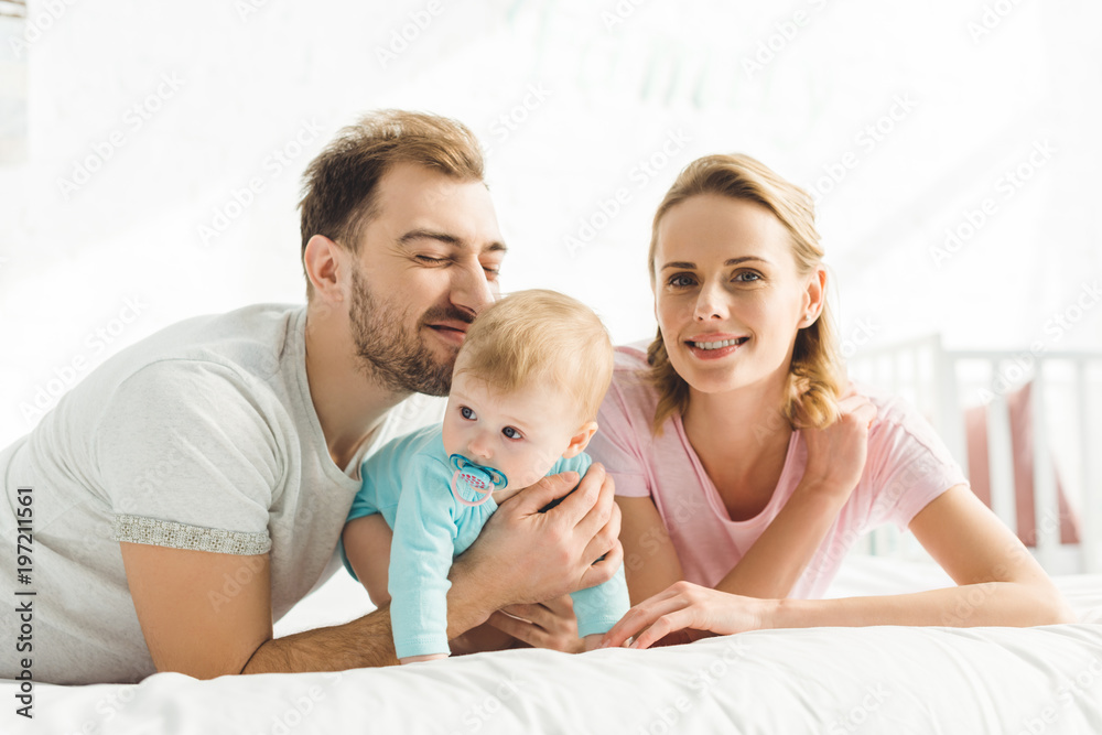 Portrait of happy family with infant daughter with baby dummy Portrait of happy family with infant daughter with baby dummy