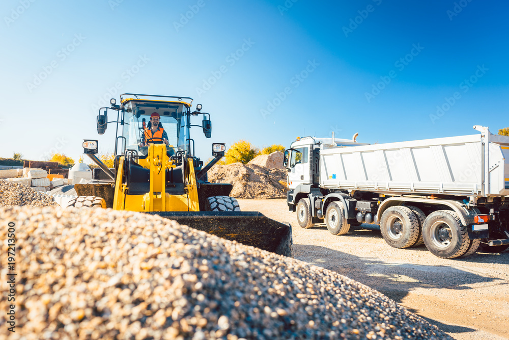 Obraz premium Arbeiter beim Tiefbau machen Erdarbeiten mit Radlader und LKW