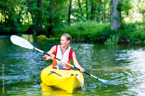 Woman paddling with canoe on forest river in summer